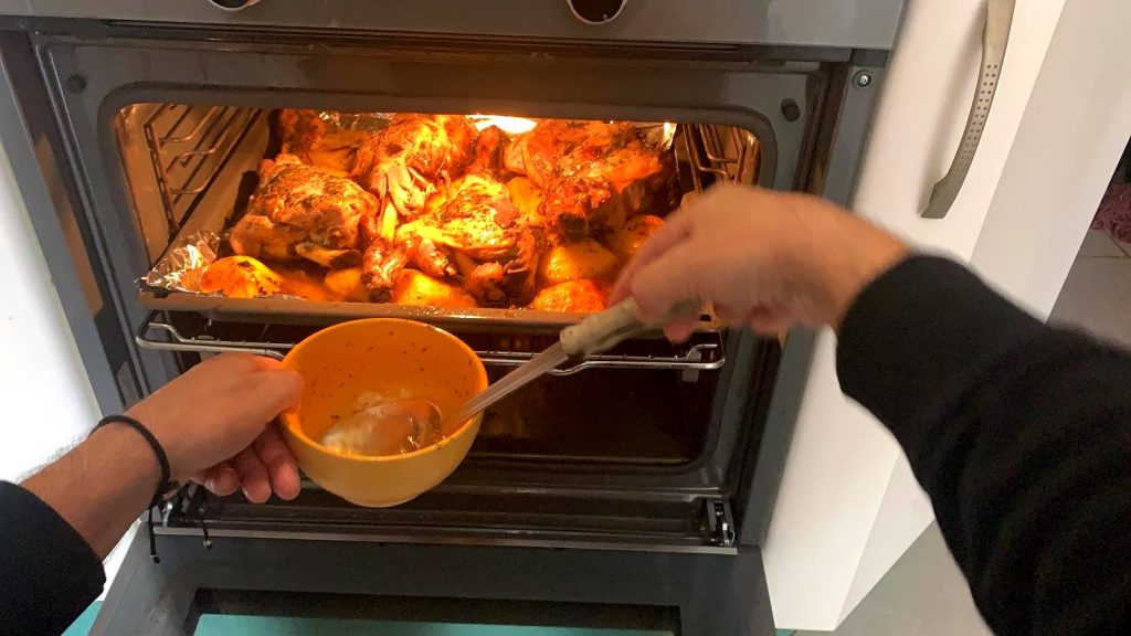 Cordero al horno con patatas, regándolo con su jugo durante el asado