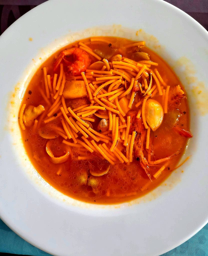 Plato de fideos con marisco: almejas, calamar y gambas en caldo